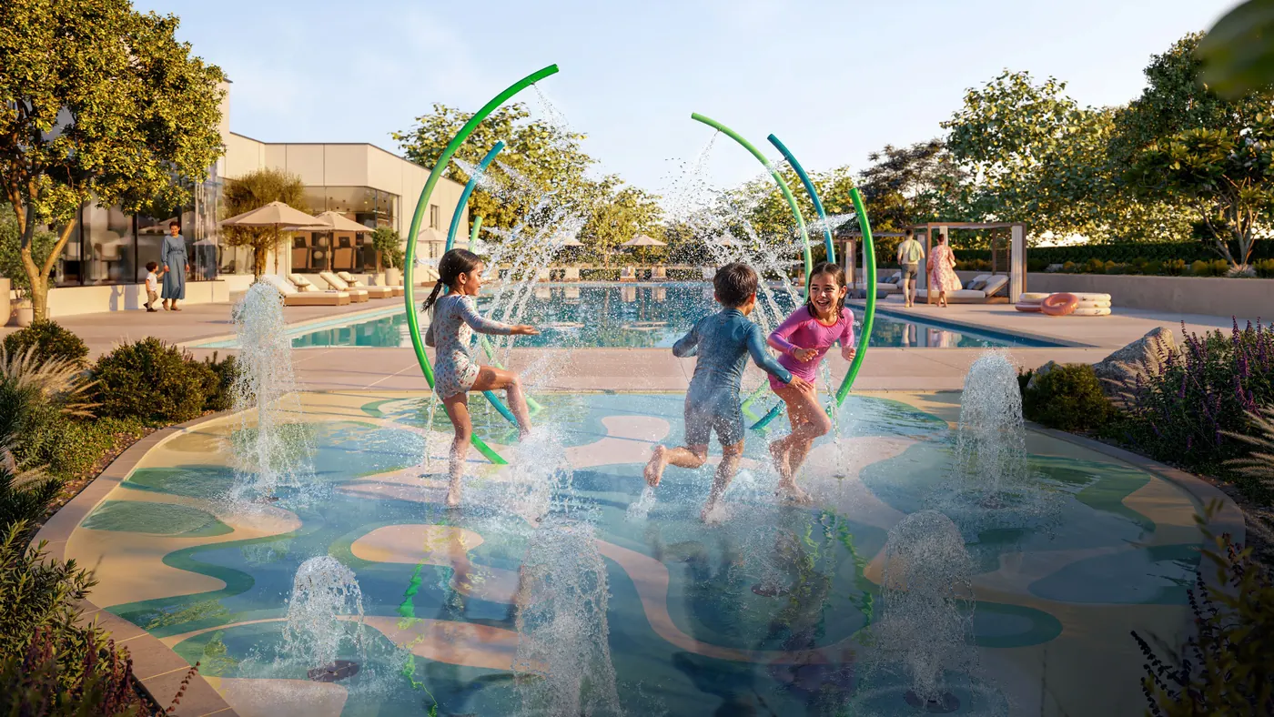 Children running through the splash pad's water arches